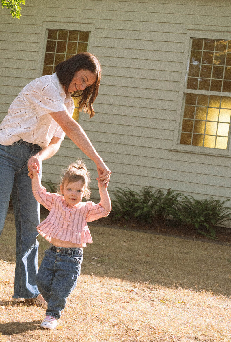 Mother holding hands with her young daughter during candid family photos in Irvine.