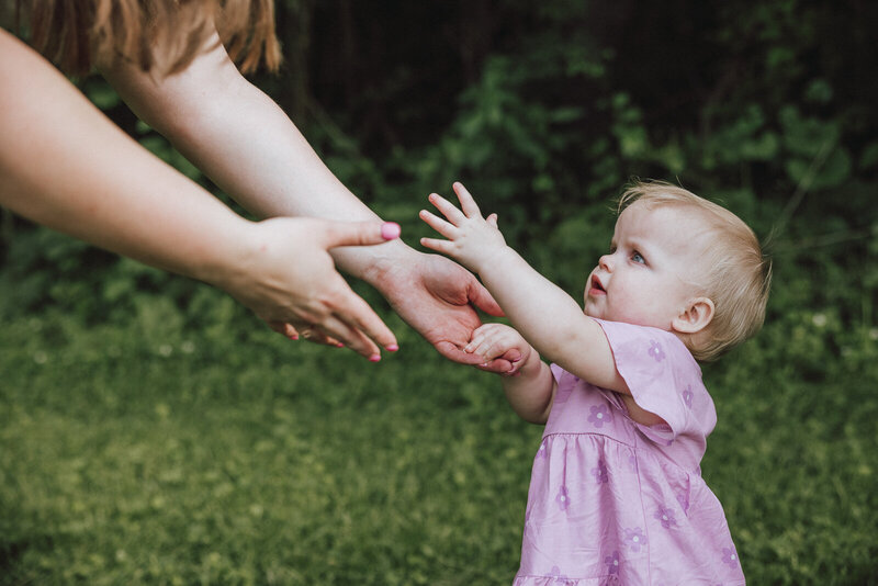 Close up of baby girl reaching for her mother's hands during a family session in De Soto, Missouri. 