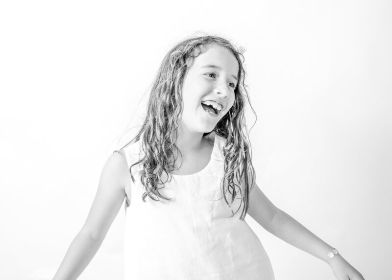 Smiling young girl in modern black and white portrait taken at Michelle Coombs’ Deltona photo studio.