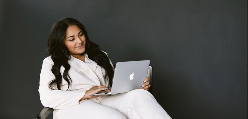 Women sitting, looking at laptop, black background