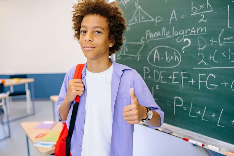 a happy student standing in front of their math work at the chalkboard