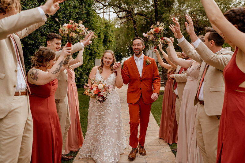 A bride and groom walking through a tunnel of their guests.