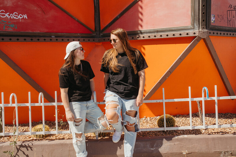 Two friends talking outside in front of a red building