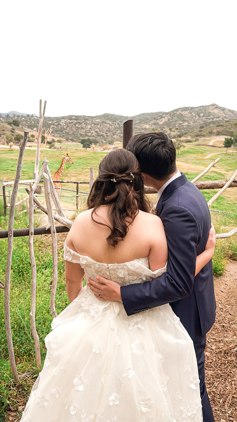 Bride and groom looking out at the giraffes at San Diego Safari Park in Escondido, California.