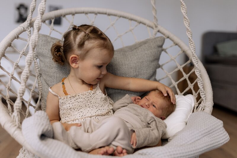 Maedchen und Baby sitzen in einer Schaukel