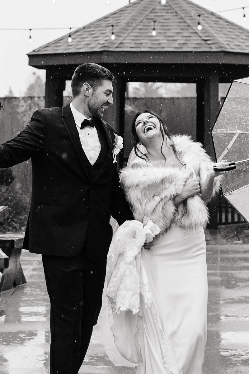 Newlyweds romp in the rain with umbrella