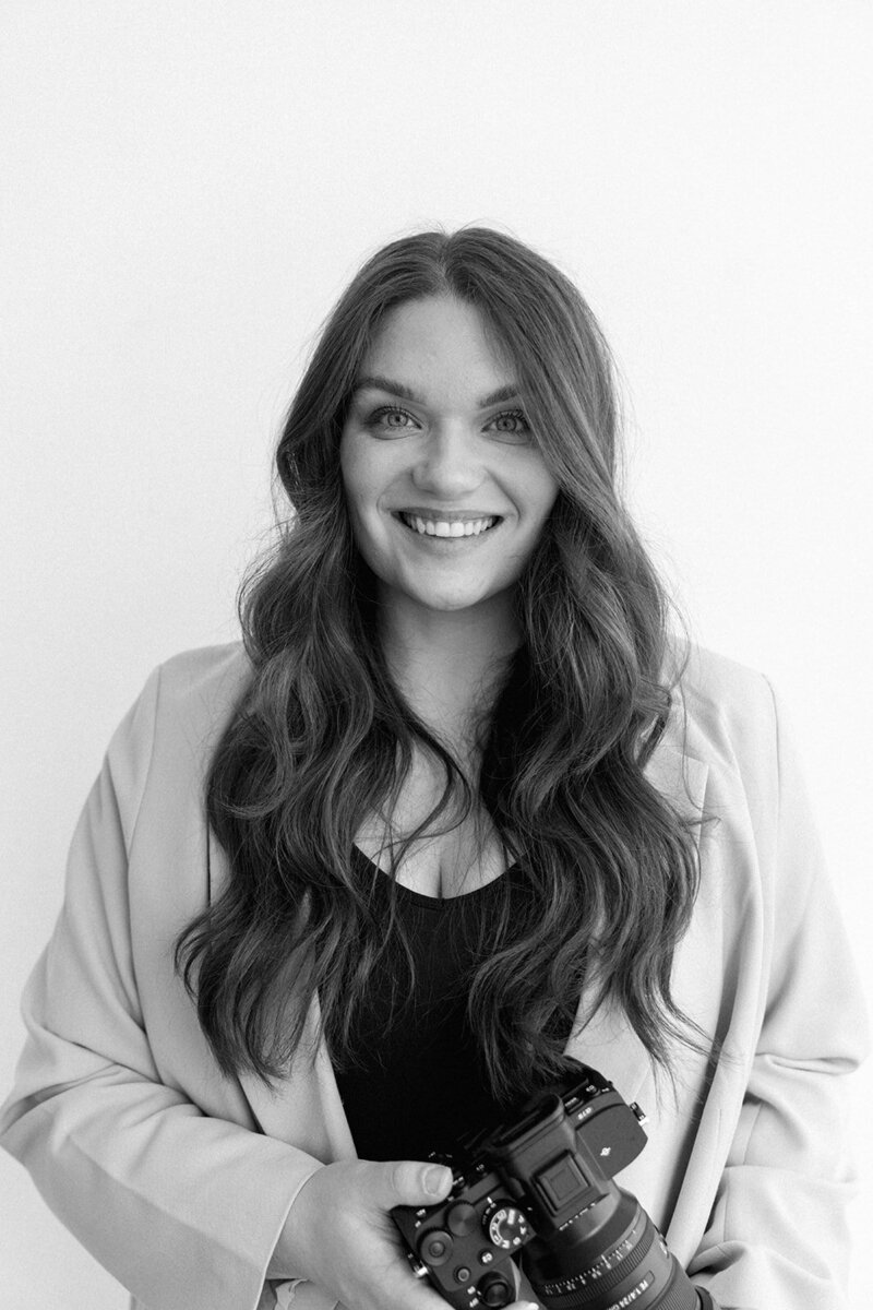 Portrait of wedding photographer Raechel Marie smiling while holding camera.