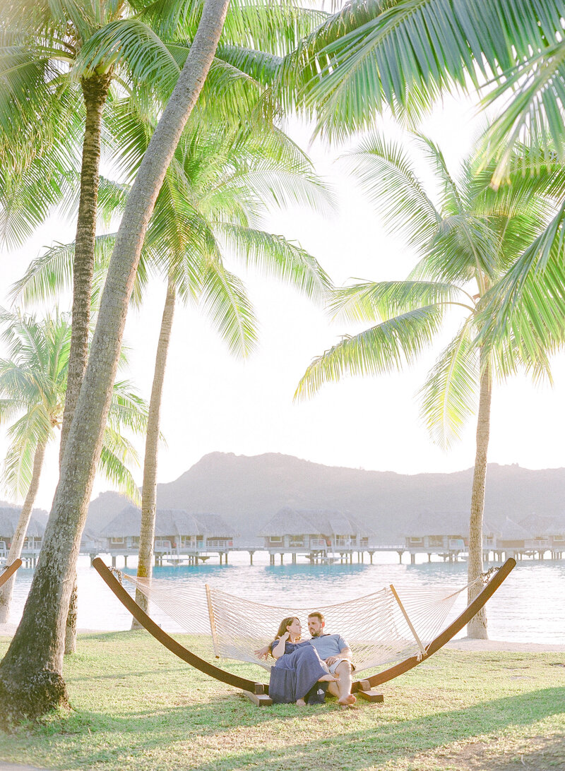 A couple on the hammock relaxing in Bora Bora, view on the lagoon, mountain and overwater bungalow