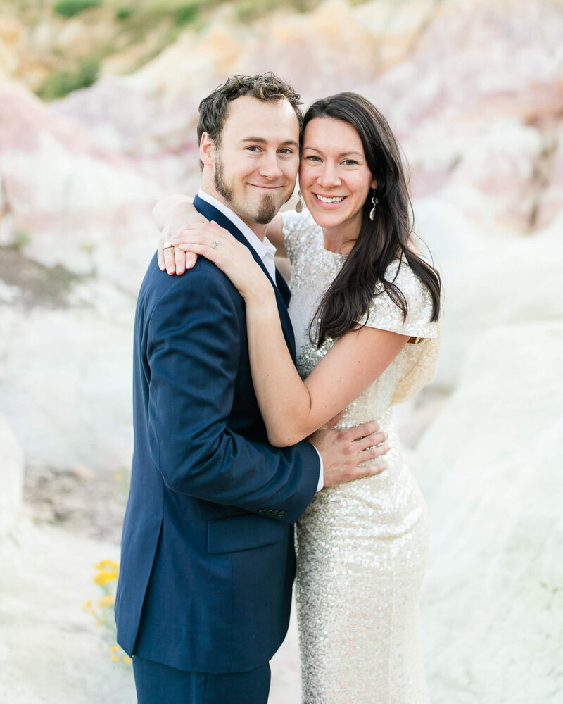 Close up portrait of a couple smiling while standing on white rocks.