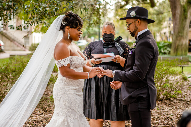 A stylish Black couple exchanges rings during their intimate micro wedding ceremony, officiated by Atosha Barboza-Bennett of Larger Than Life Events & Behind the Veil Academy. A perfect union captured beautifully.