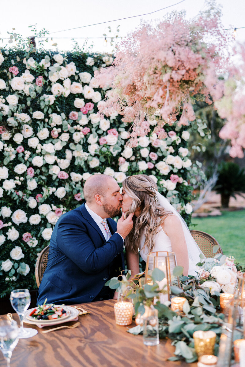 Bride and groom sit at a table and kiss