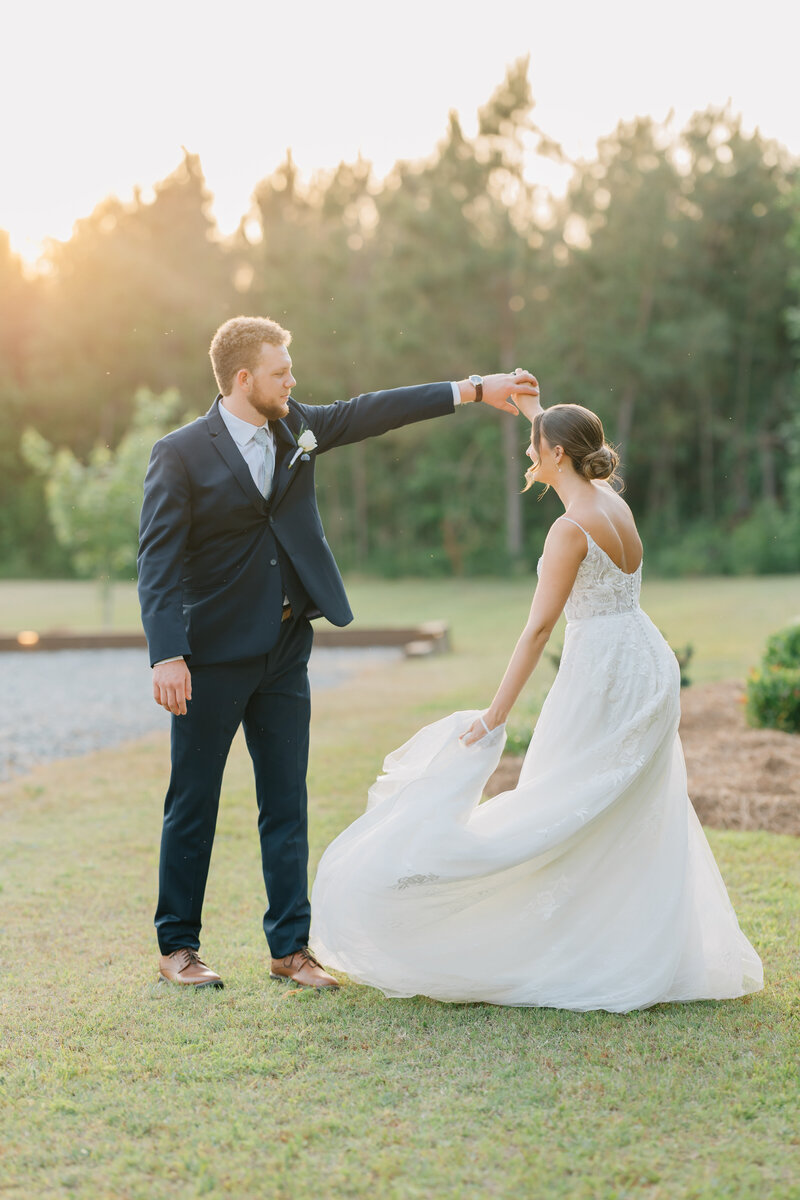 groom twirling bride as sun sets in the background