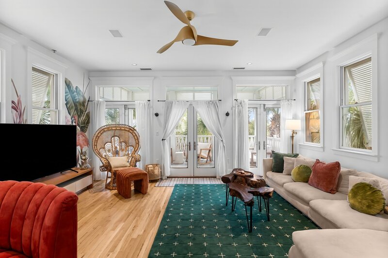 Light-filled living room with tropical accents, cozy sectional, and access to balconies at The Florida House, a Carillon Beach house rental near 30A and Grayton Beach.
