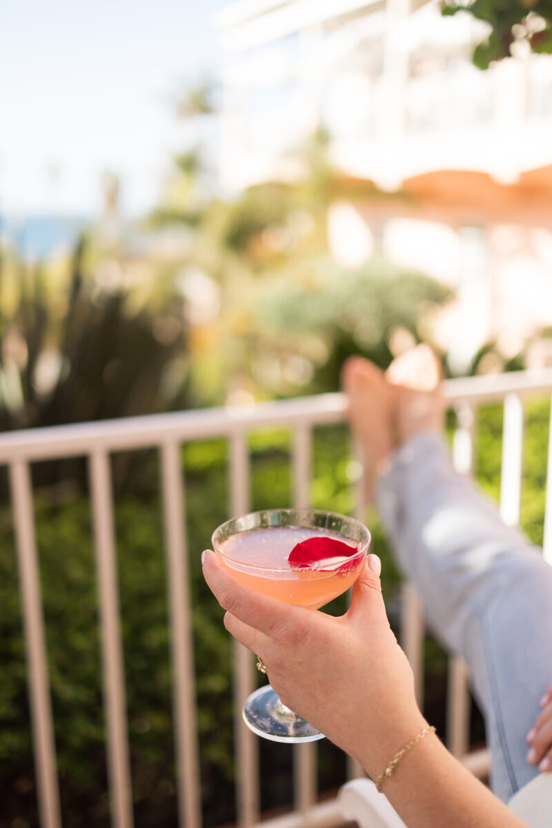 Hand holding a pink cocktail with a rose petal at the Valencia Hotel in La Jolla