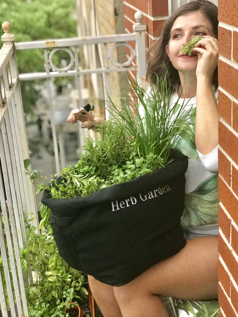 Woman smells herbs from her Gardenuity herb garden
