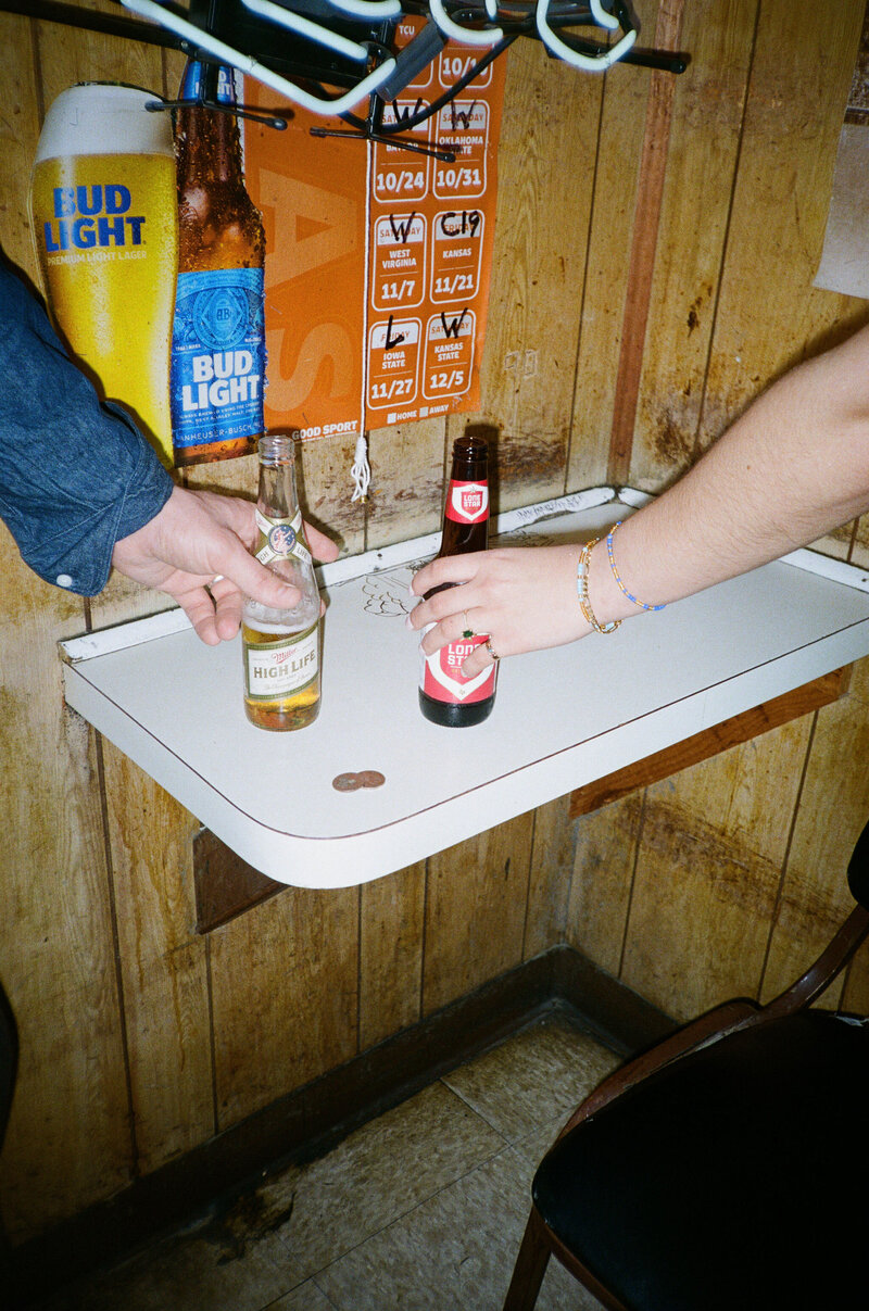 zoomed in photo of couple celebrating their engagement with beers at Deep Eddy's Cabaret in Austin, TX