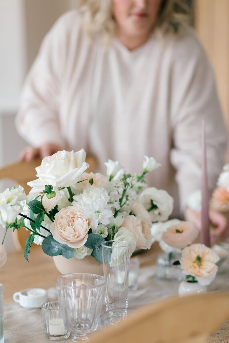 A large tall glass vase of eucalyptus foliage, trailing jasmine and white flowers.