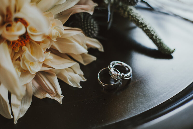 wedding rings on a side table next to yellow flowers