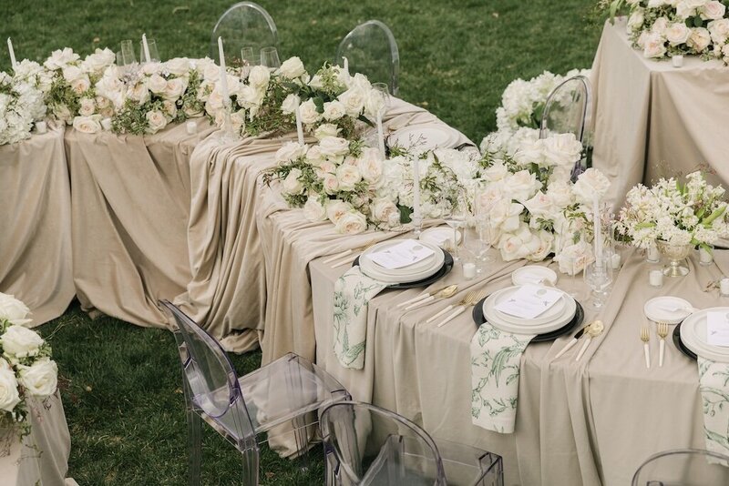 Gorgeous serpentine wedding reception table draped in pink linens and covered in luxury white florals at a chateaux wedding venue near Denver