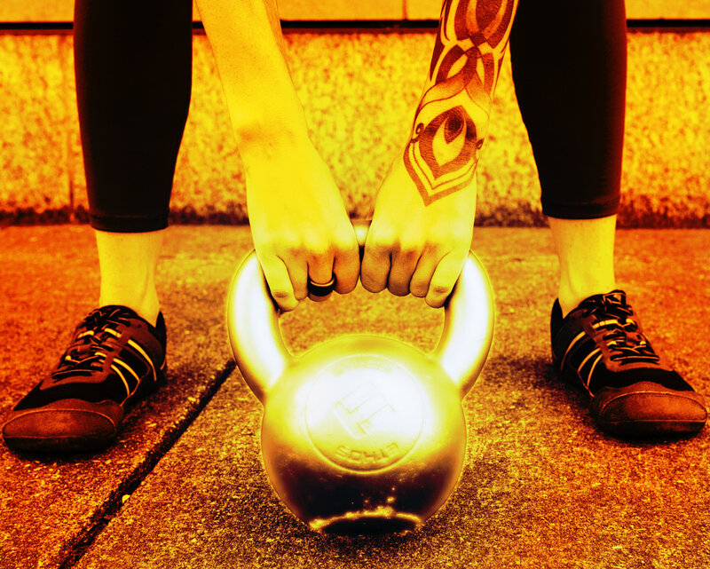 a person holds a glowing kettlebell in the hike position