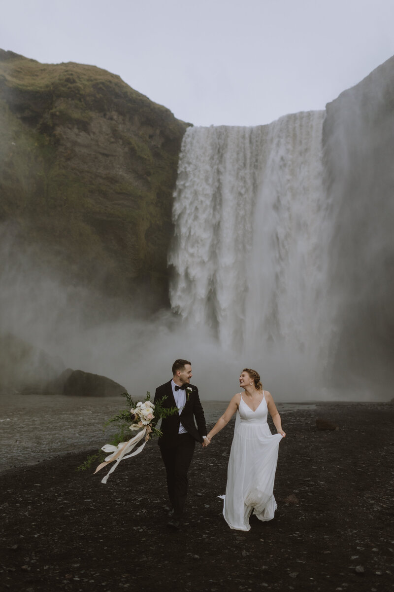 bride and groom in front of waterfall