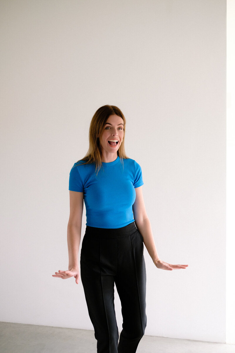 A woman strikes a pose in front of a large window, with gentle natural light creating soft shadows around her.