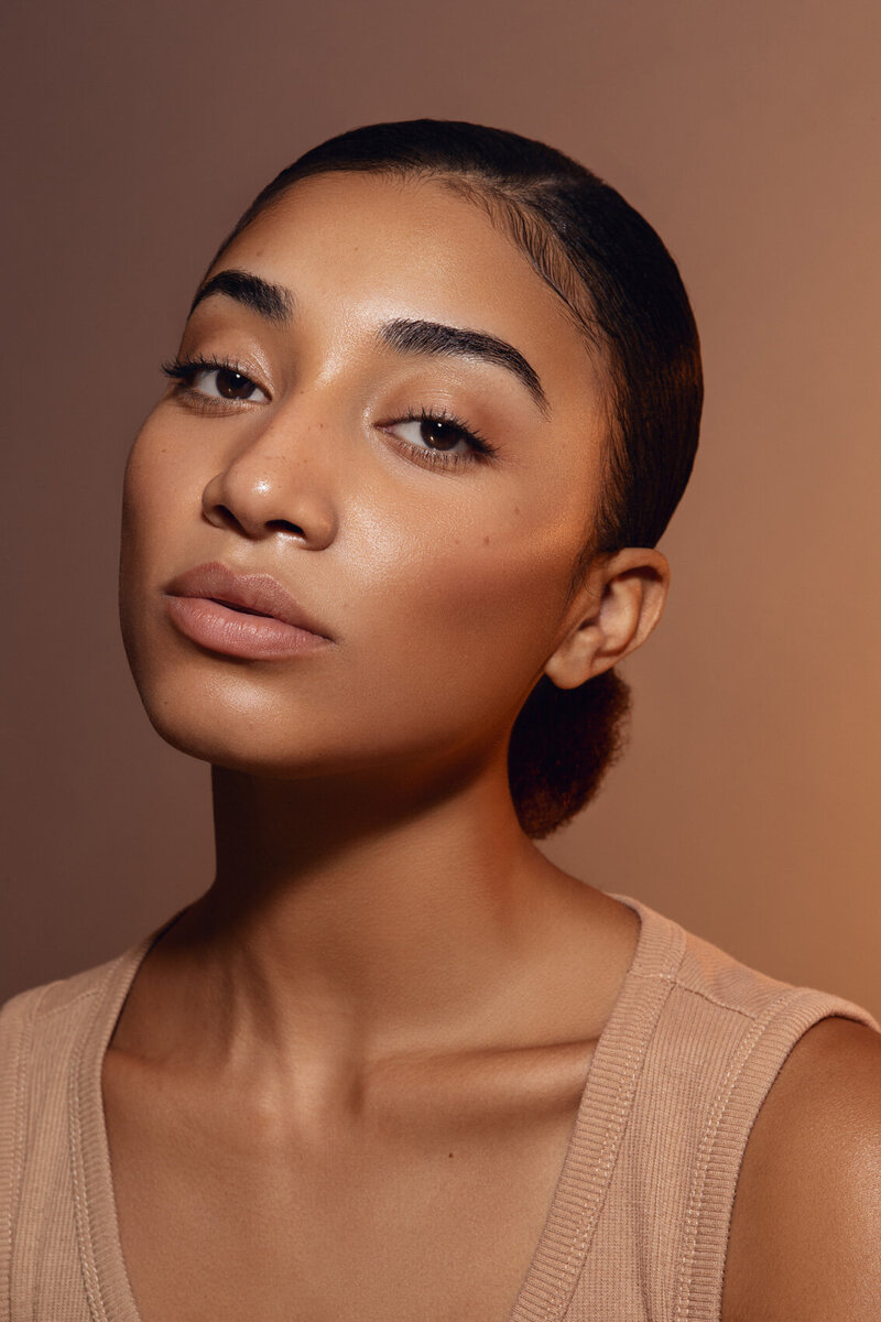 Tajah Moore in a close-up beauty portrait with natural makeup and a serene expression, photographed by Ylva Erevall.