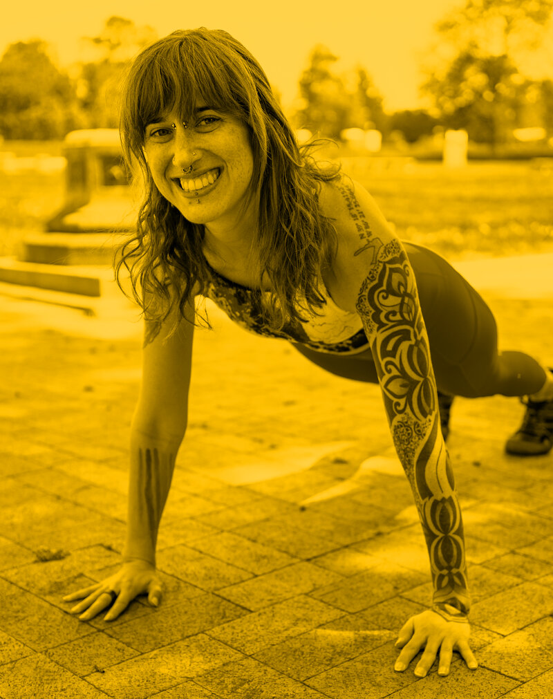 a woman does a high plank with a smile outside on brick, yellow overlay