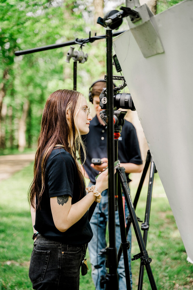storyteller team member payton mccabe stands behind lighting equipment on location outdoors