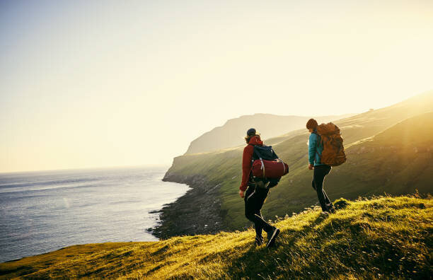 Two people backpacking out in nature with the ocean in the background