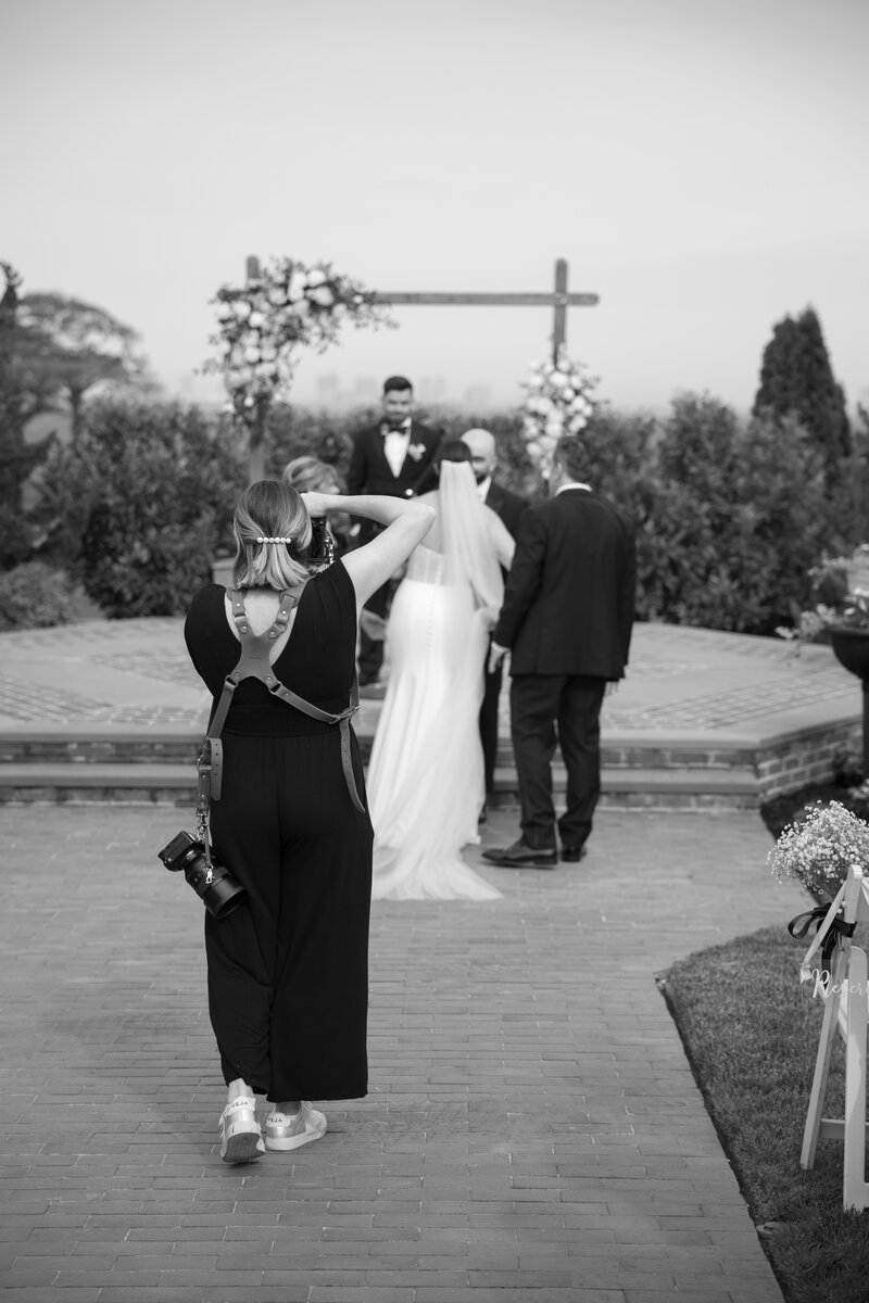 Black and white image of headshot of Jordan Simone New Jersey photographer taking photos during wedding ceremony