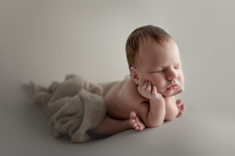 A peaceful side view of the classic froggy pose—newborn boy in soft neutrals, captured in Paris, Ontario.