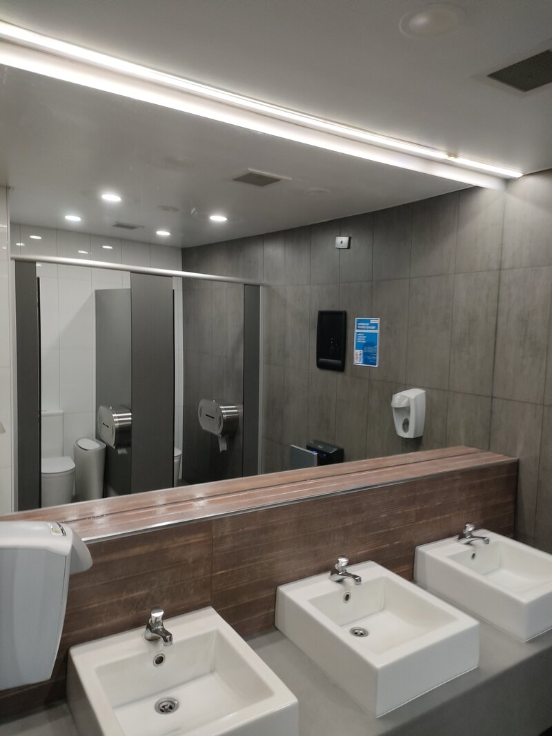Modern commercial bathroom featuring custom frameless mirrors, designed for durability and a sleek aesthetic.