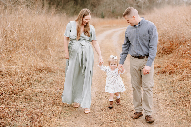 Photo of family walking and holding  hands at their maternity session at Cibolo Nature Center in San Antonio