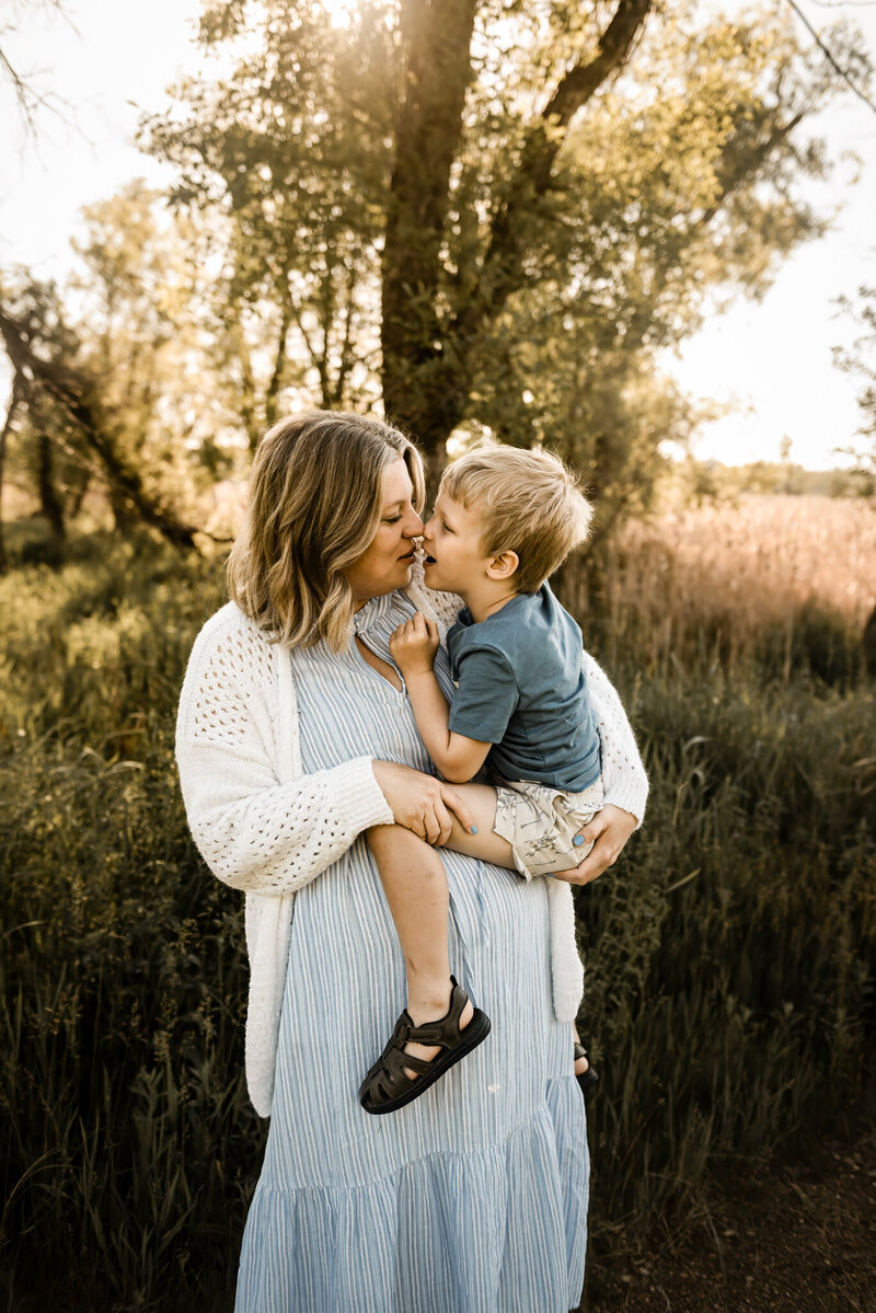 A momma holds tight to her baby boy while dancing around the golden sunrise during a family session near Bismarck, ND