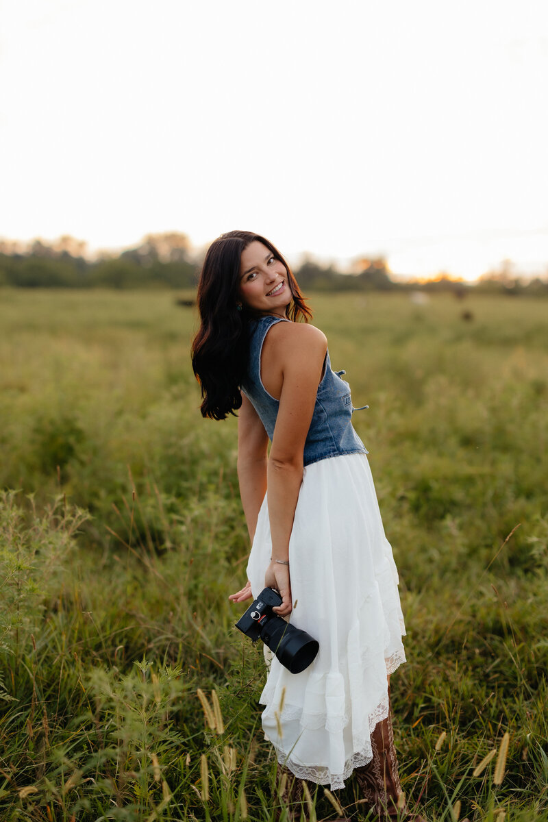 Woman in a field with a camera in hand