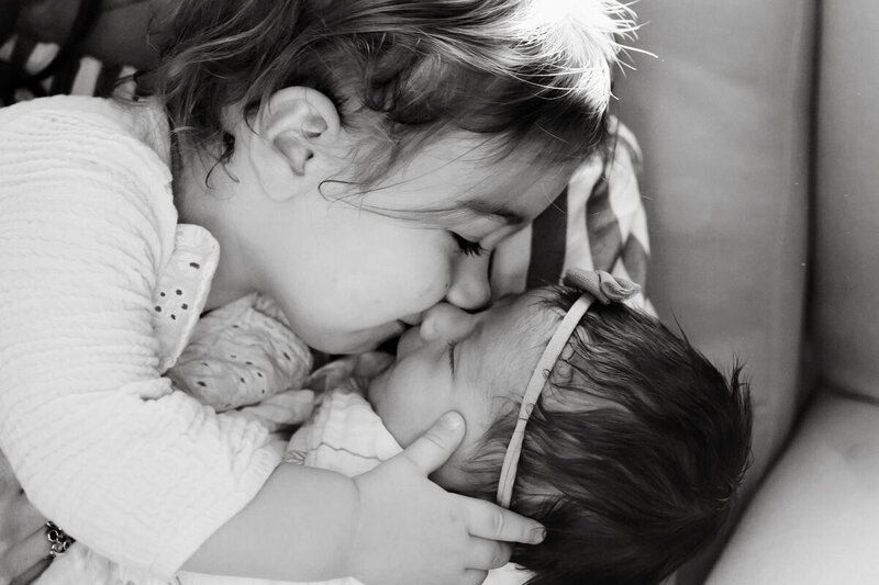 toddler kissing newborn