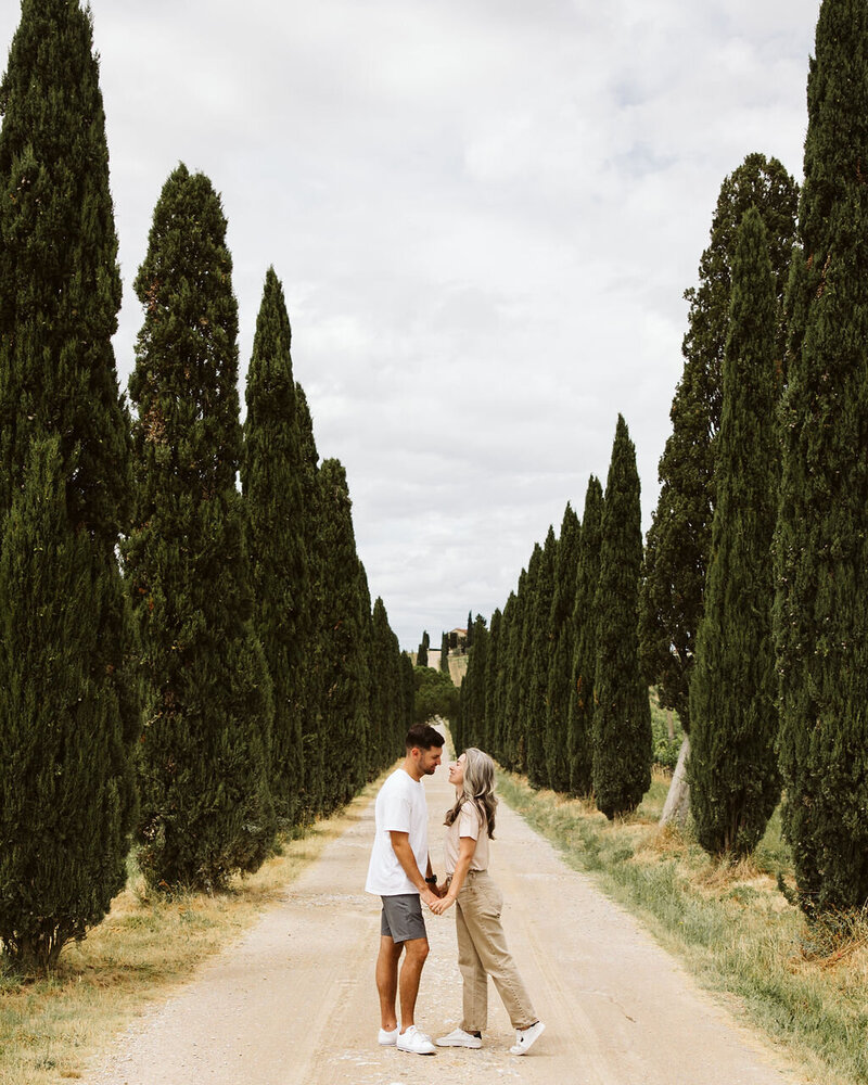 Destination wedding planning team posing along cypress-lined dirt road in Tuscany, Italy!