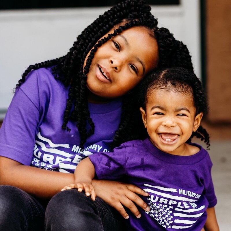 Two kids smiling wearing purple up tshirt