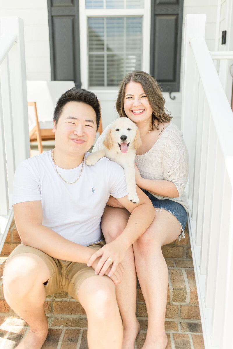 Male, female, and puppy sitting on porch steps