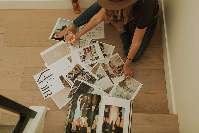 Woman sitting on floor with stacks of photos and magazines