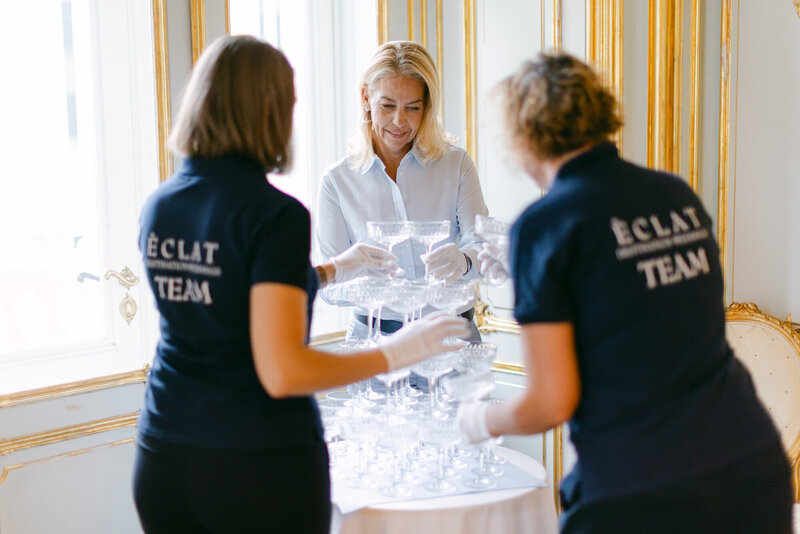Team of ÈCLAT Destination Weddings preparing champagne tower at majestic Palace Coburg in Vienna