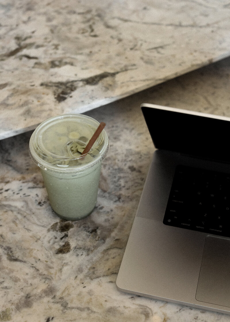 iced coffee and a computer sitting on a granite countertop
