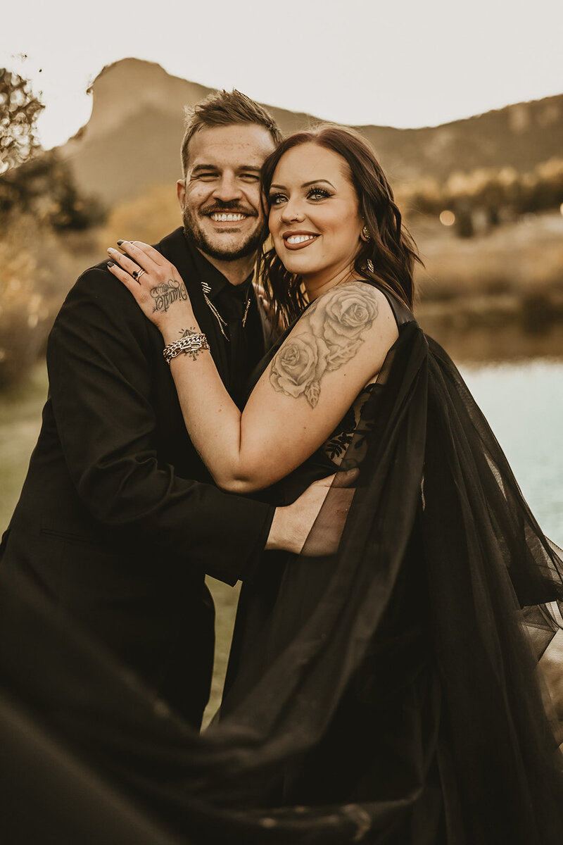 Colorado October fall wedding at Wedgewood Weddings at Mountain View. Til Death Do Us Part wedding inspo. Blacvk wedding dress with black angel wings and the groom in a black tuxedo with tux skull accents