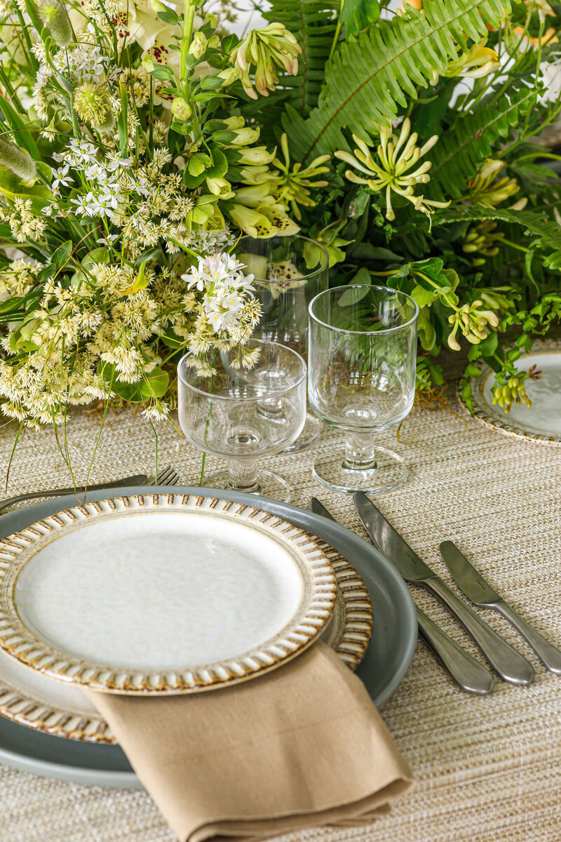 Cream and tan porcelain dishes with embossed edges placed for wedding reception
