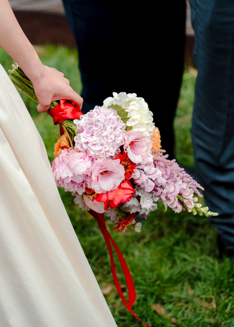 A tightly cropped shot of a brides hand holding a colour floral wedding bouquet