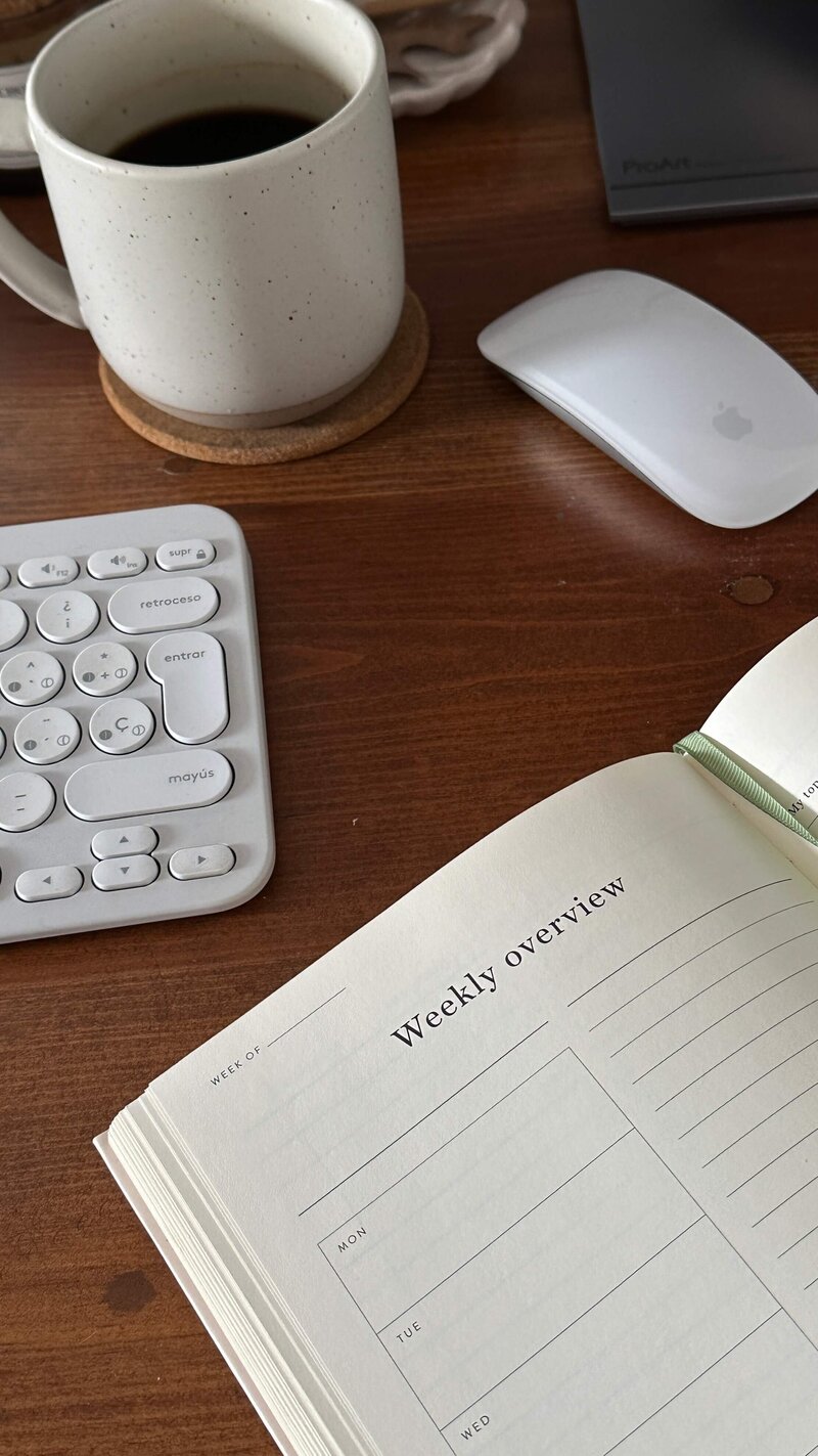 A planner, coffee and keyboard on a desk, representing event guidance and planning services offered by Perfect Thirds & Co. 