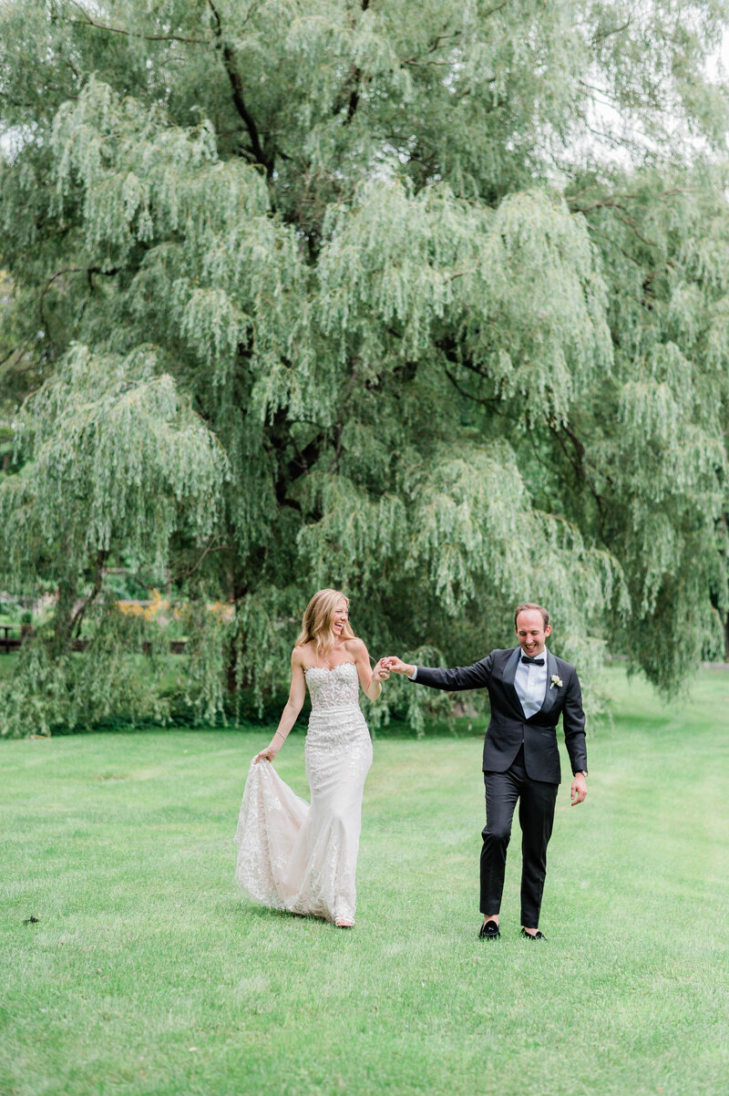 Wife smiles at her husband while they walk side by side in the grass
