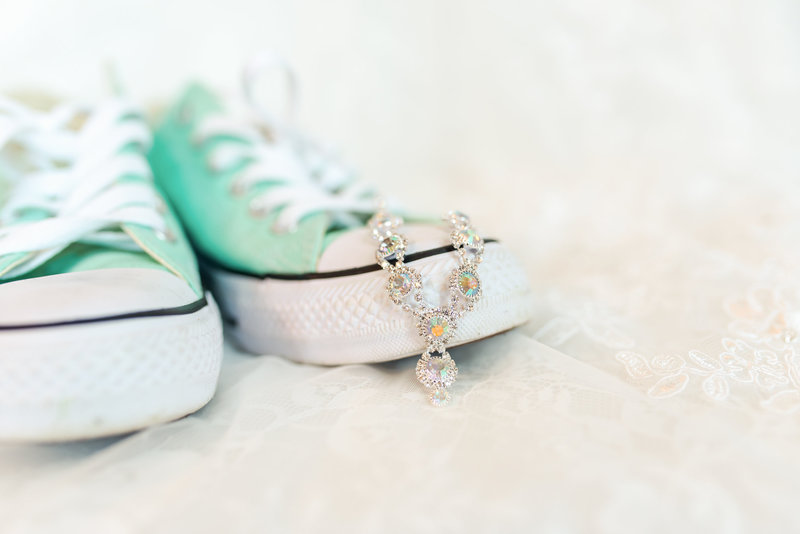 Wedding jewelry sit on sage colored Converse sneakers