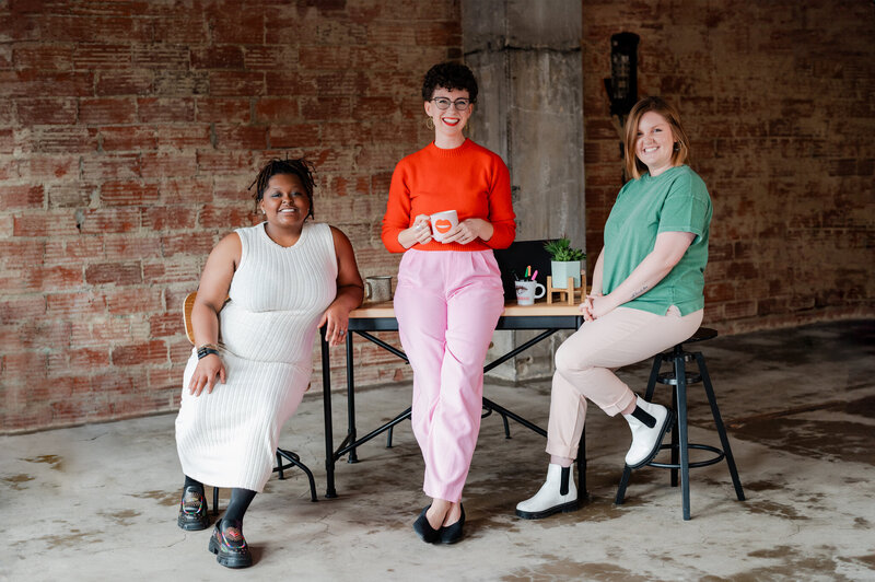 Group of event and wedding planners in bright colors  sitting at a desk